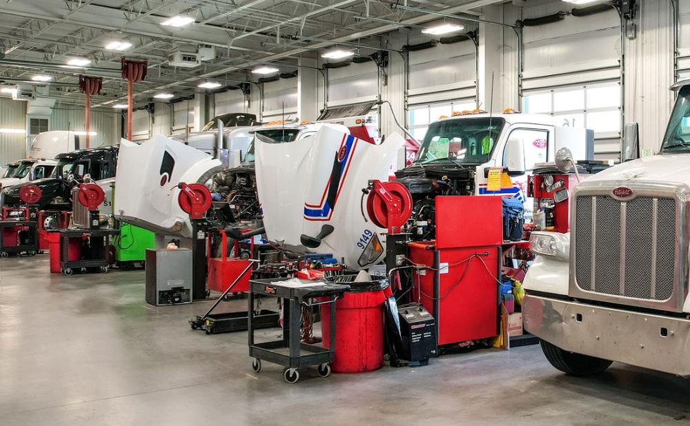 A row of Peterbilt trucks being serviced at a semi truck repair shop