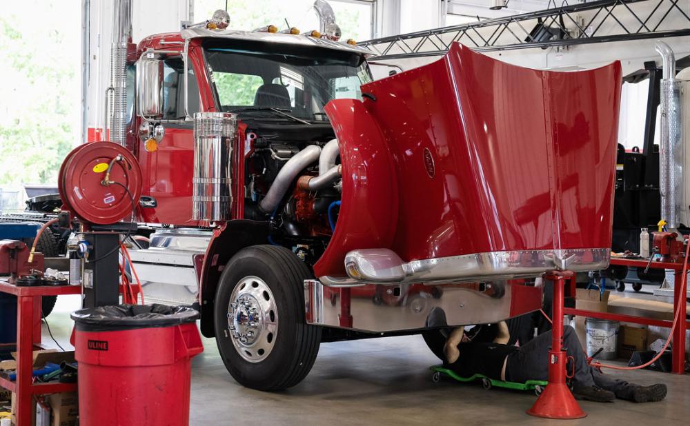 A Diesel Technician doing an oil change on a red Peterbilt Model 589